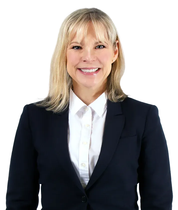 Person with blonde hair wearing a dark blazer and white shirt, smiling at the camera against a plain background.